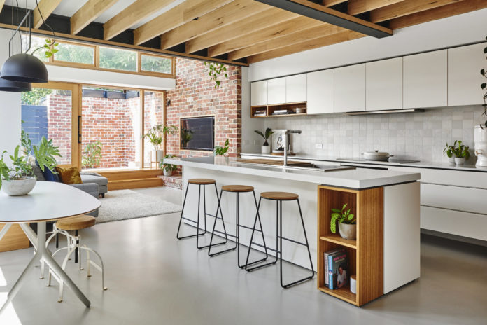 Eco friendly kitchen with wooden beams, white cabinetry and breakfast bar